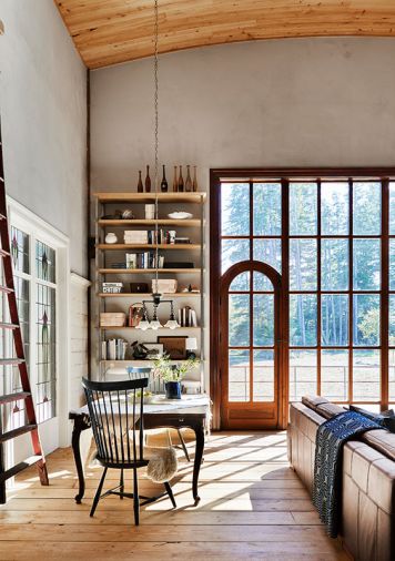 Casual living is enhanced by the rough-sawn 12' plank flooring, this corner is a perfect spot for game night and puzzles. The wooden picture window with an integrated arched doorway shows Arciform’s precision and detail found throughout the home. The white oak and steel shelving offers a place for keepsakes and books while a vintage orchard ladder gives access to high shelves. Casual living is enhanced by the rough-sawn 12' plank flooring, this corner is a perfect spot for game night and puzzles. The wooden picture window with an integrated arched doorway shows Arciform’s precision and detail found throughout the home. The white oak and steel shelving offers a place for keepsakes and books while a vintage orchard ladder gives access to high shelves.