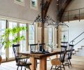 Antique church chandeliers were salvaged to light Richard’s massive table and sheepskins soften the dining room chairs. Arciform crafted the transom window that sits atop the stained-glass door, matching the door height. Antique church chandeliers were salvaged to light Richard’s massive table and sheepskins soften the dining room chairs. Arciform crafted the transom window that sits atop the stained-glass door, matching the door height.