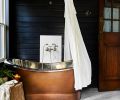 A copper soaking tub with nickel plated interior from Signature Hardware pops against the blackened walls. A copper soaking tub with nickel plated interior from Signature Hardware pops against the blackened walls.