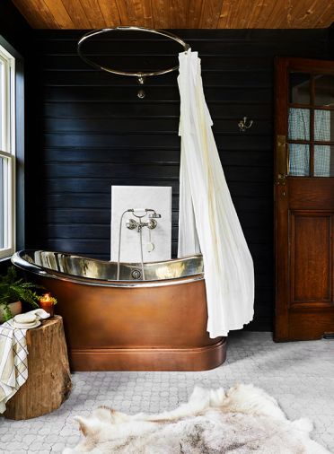 A copper soaking tub with nickel plated interior from Signature Hardware pops against the blackened walls. A copper soaking tub with nickel plated interior from Signature Hardware pops against the blackened walls.