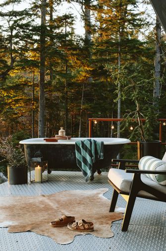 A salvaged clawfoot tub perches upon the wraparound galvanized perforated metal decking, assuring privacy thanks to the well-forested 12-acre plot of land. A Room & Board Breeze chair awaits alongside. A salvaged clawfoot tub perches upon the wraparound galvanized perforated metal decking, assuring privacy thanks to the well-forested 12-acre plot of land. A Room & Board Breeze chair awaits alongside.