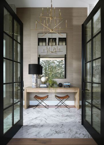 Marble covers the entry floor and a candle-style chandelier lights the way. The leather stools, desk, oversized mirror, and elegant Phillip Jeffries wallcovering are welcoming. Marble covers the entry floor and a candle-style chandelier lights the way. The leather stools, desk, oversized mirror, and elegant Phillip Jeffries wallcovering are welcoming.