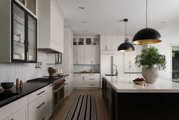 Entertaining is made easy with an open floor plan offering clear views of the dining and living room. The two-tone kitchen has cabinetry from LCM Cabinets, painted in “Agreeable Gray” and “Tricorn Black”. Entertaining is made easy with an open floor plan offering clear views of the dining and living room. The two-tone kitchen has cabinetry from LCM Cabinets, painted in “Agreeable Gray” and “Tricorn Black”.