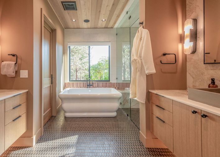 Various natural materials were combined for a welcoming primary bathroom, including fluted lapidary tile from Clé that adds depth behind the freestanding tub and continues into the shower. The wood ceiling syncs with the rift white oak cabinetry and Ann Sacks floor tile. Various natural materials were combined for a welcoming primary bathroom, including fluted lapidary tile from Clé that adds depth behind the freestanding tub and continues into the shower. The wood ceiling syncs with the rift white oak cabinetry and Ann Sacks floor tile.