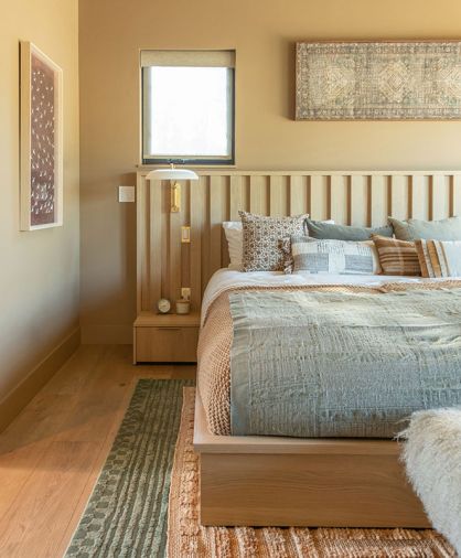 The custom bedframe with integrated nightstands for the couple’s nine-foot-wide mattress was designed by Shannon, so the whole family and two dogs can pile in at once. Sherwin Williams “Rookwood Clay” dresses the walls. The custom bedframe with integrated nightstands for the couple’s nine-foot-wide mattress was designed by Shannon, so the whole family and two dogs can pile in at once. Sherwin Williams “Rookwood Clay” dresses the walls.