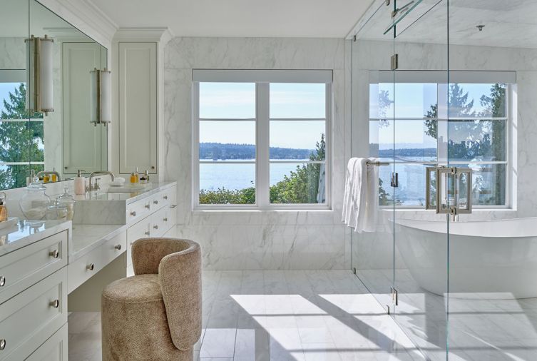 The completely redesigned primary bath glows with exquisite slabs of flow-matched Calacatta Caldia marble honed across every surface. Custom floating dual vanities by Barneswood Custom Cabinets with makeup chair offer views of Lake Washington. The completely redesigned primary bath glows with exquisite slabs of flow-matched Calacatta Caldia marble honed across every surface. Custom floating dual vanities by Barneswood Custom Cabinets with makeup chair offer views of Lake Washington.